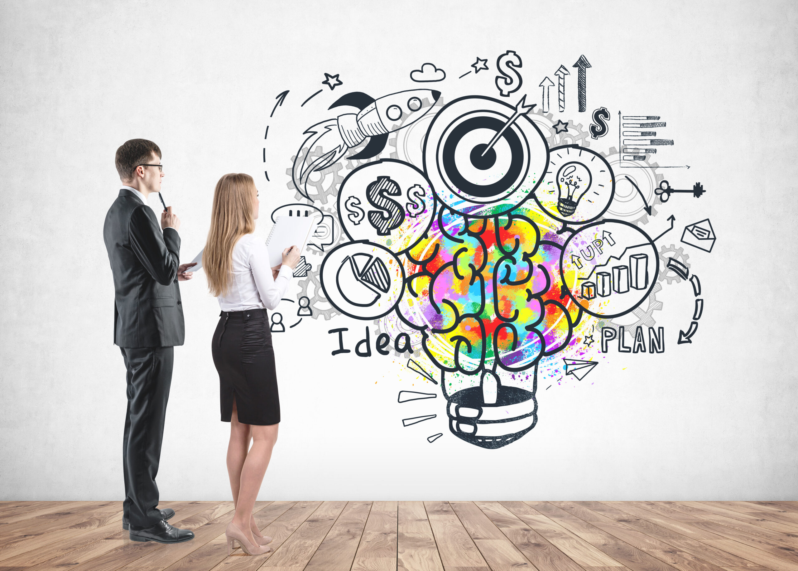 Business partners developing business idea Two young business partners with documents looking at concrete wall with colorful business idea sketch drawn on it. Concept of brainstorming